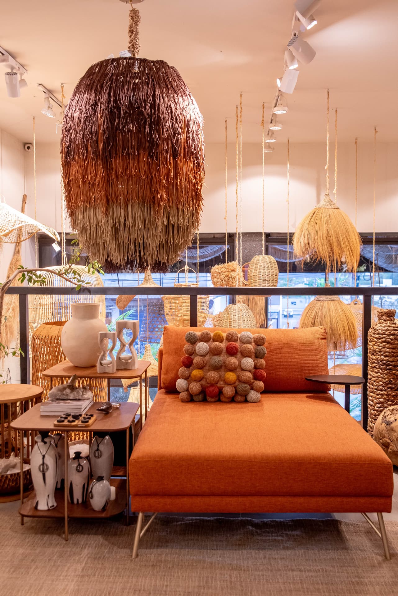 Ambiente curado com poltrona terracota, luminárias de fibra natural e objetos de arte brasileira